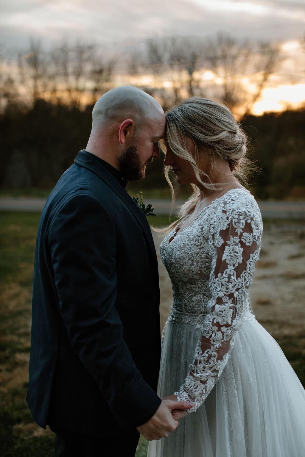 Romantic sunset wedding photos with couple in lace dress and black suit.