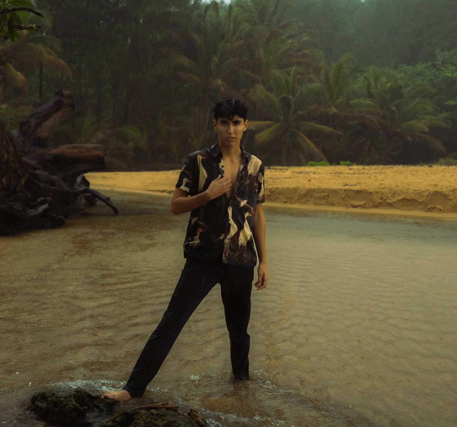 boy standing in the rain at a beach in moloa'a during a storm