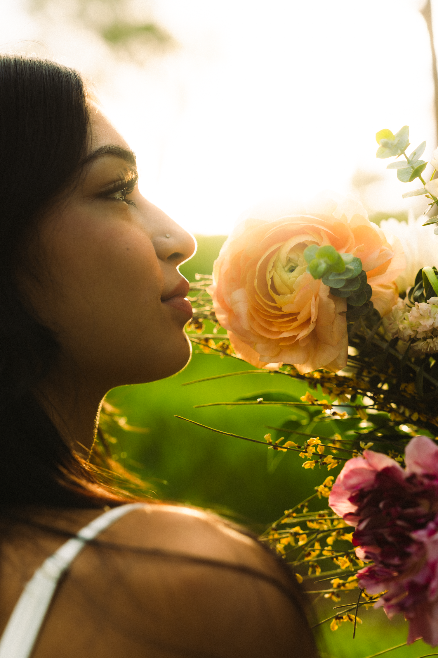graduate in the mountains of loop road kauai with a bouquet of flowers and light shining through