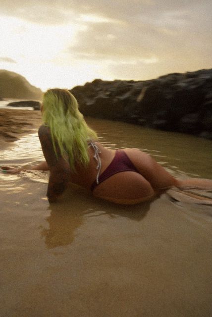 girl playing in the sand at a beach as she watches the sunset from kauai