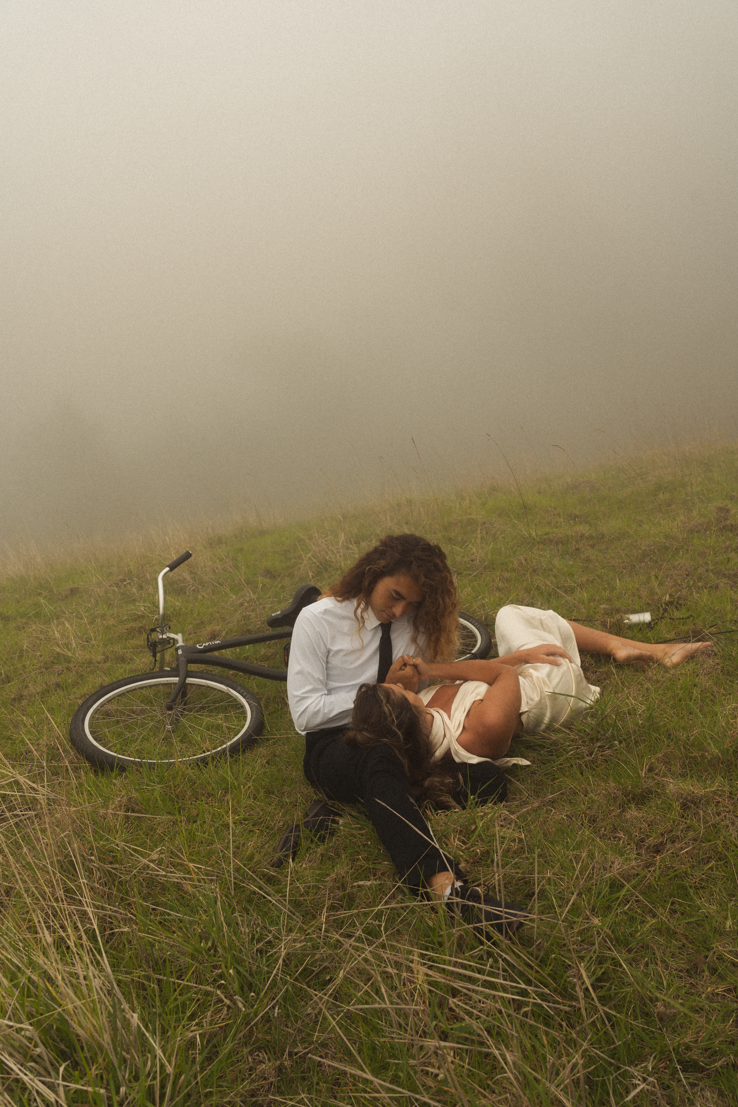 A couple playing in grassy misty fields of Hawaii during a cool evening