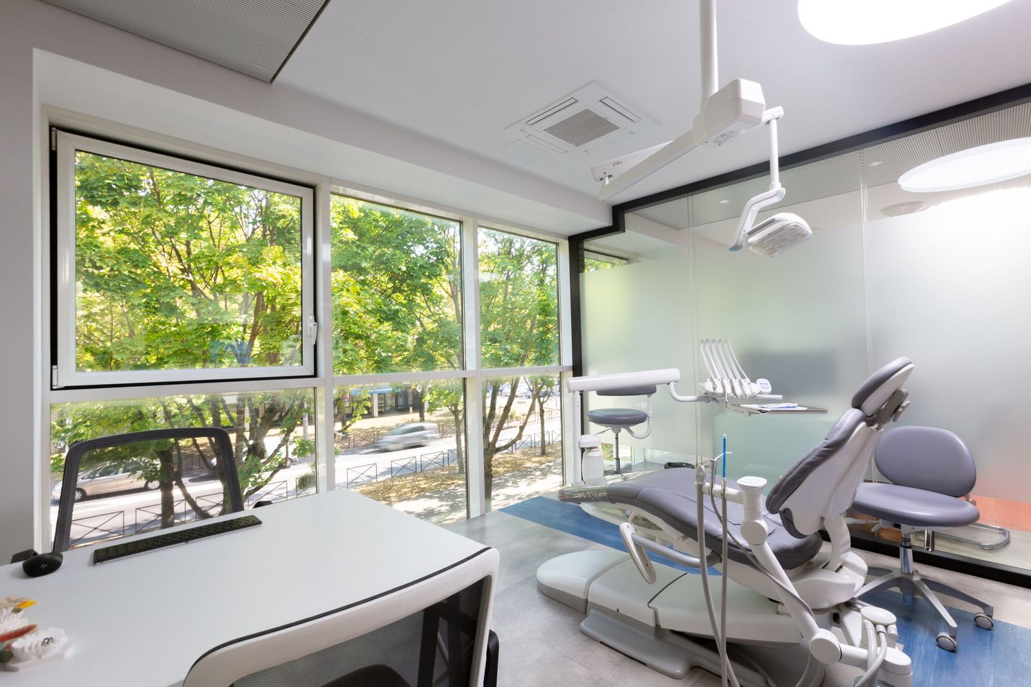 Modern dental treatment room with floor-to-ceiling windows and contemporary medical equipment.
