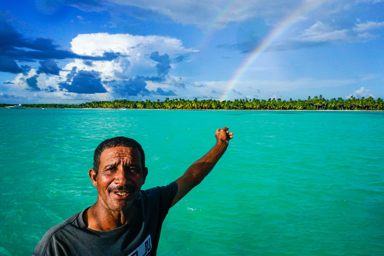 A man in the Dominican Republic points at a double rainbow. Image by Alex Kent, commercial photographer and educator