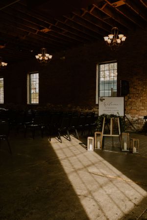 Rustic wedding ceremony venue with exposed brick walls and sunlight streaming through windows.