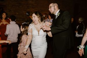 Wedding reception candid moment with guests dancing in a dimly lit brick venue.