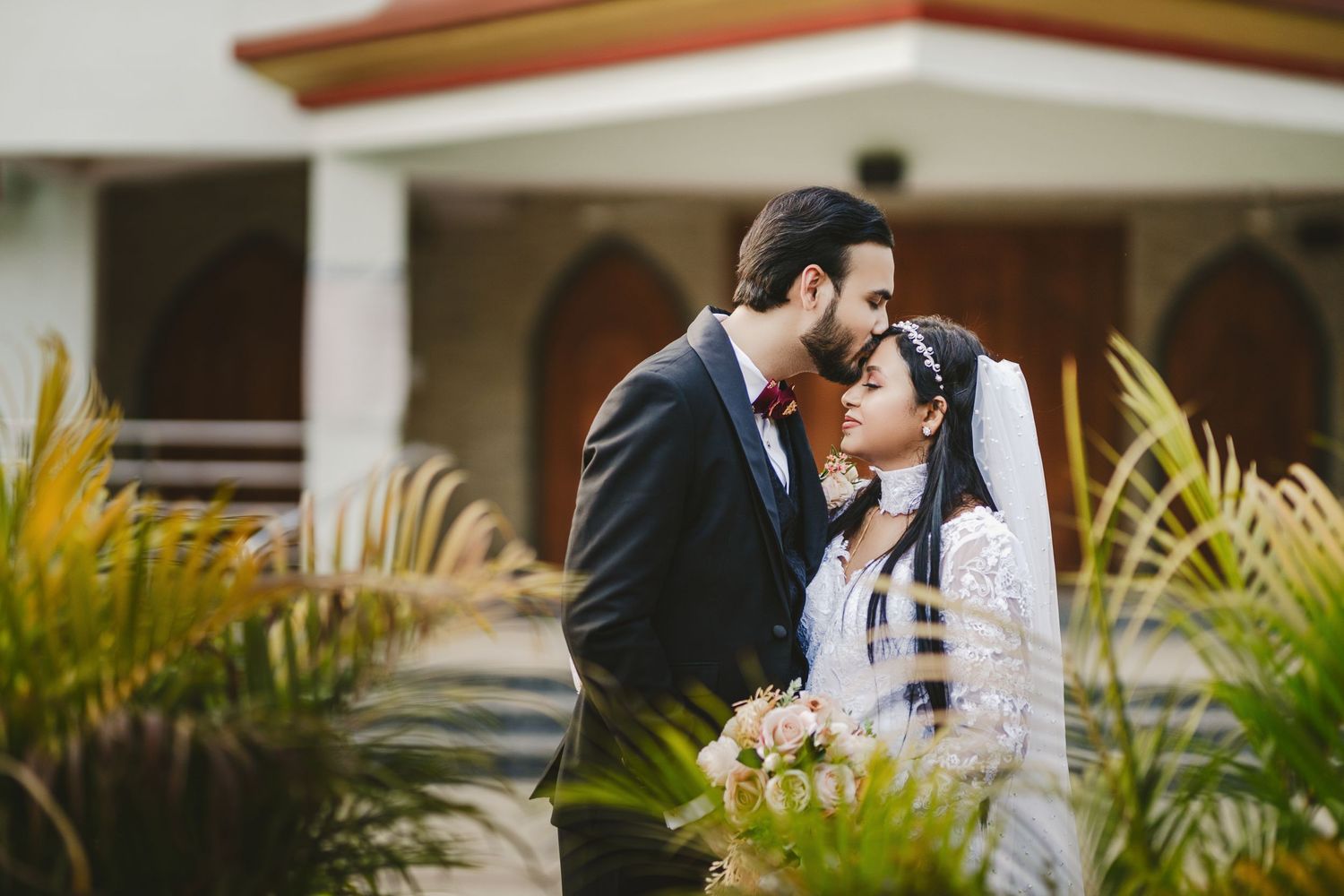 Romantic outdoor wedding portrait with palm trees and natural lighting.