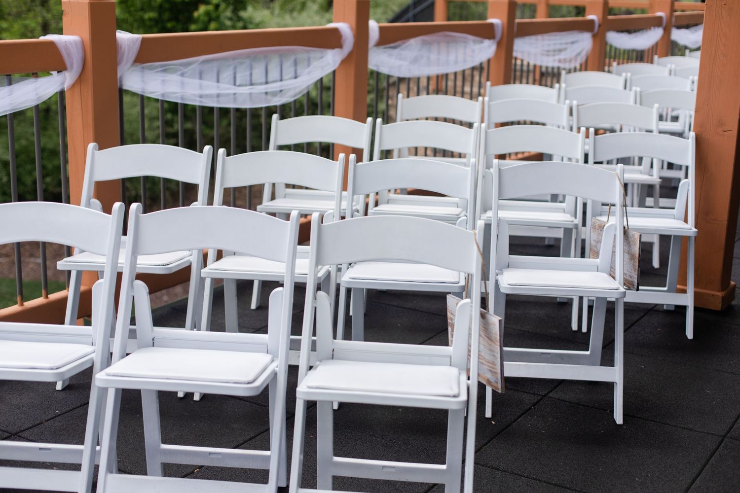 Rows of white folding chairs set up for an outdoor wedding ceremony.