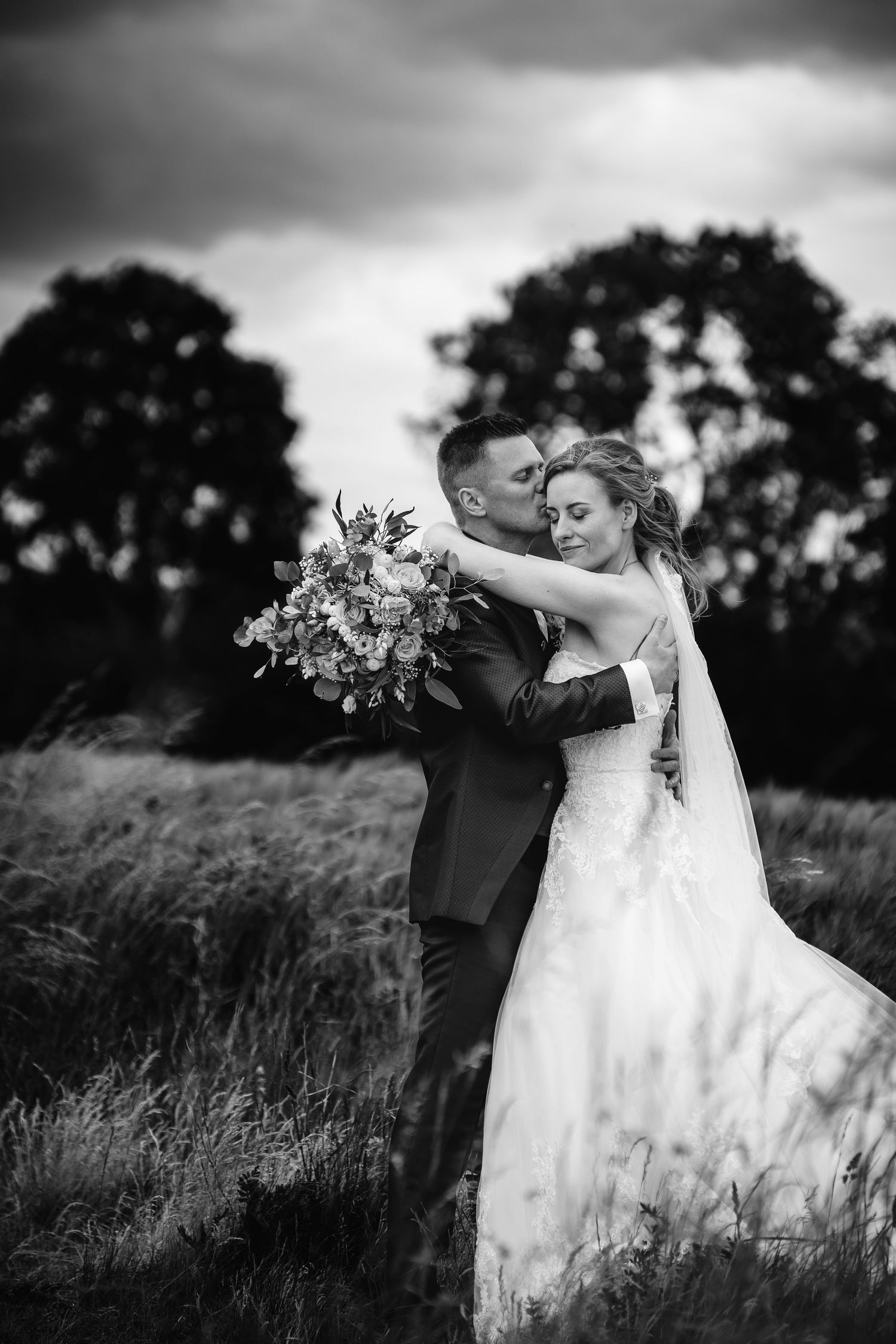 Black and white wedding portrait of couple dancing in a meadow.