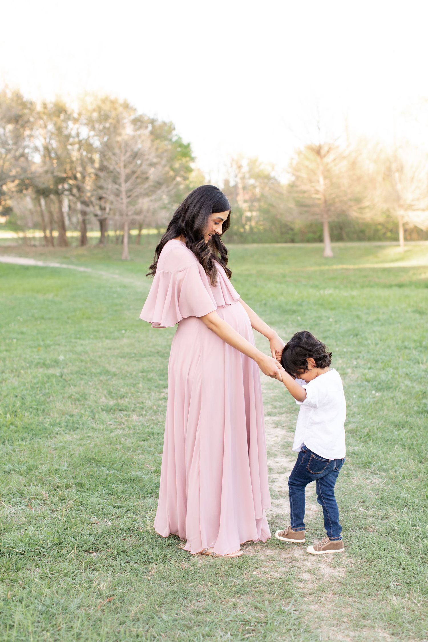 A tender interaction between adult and child on a grassy path.