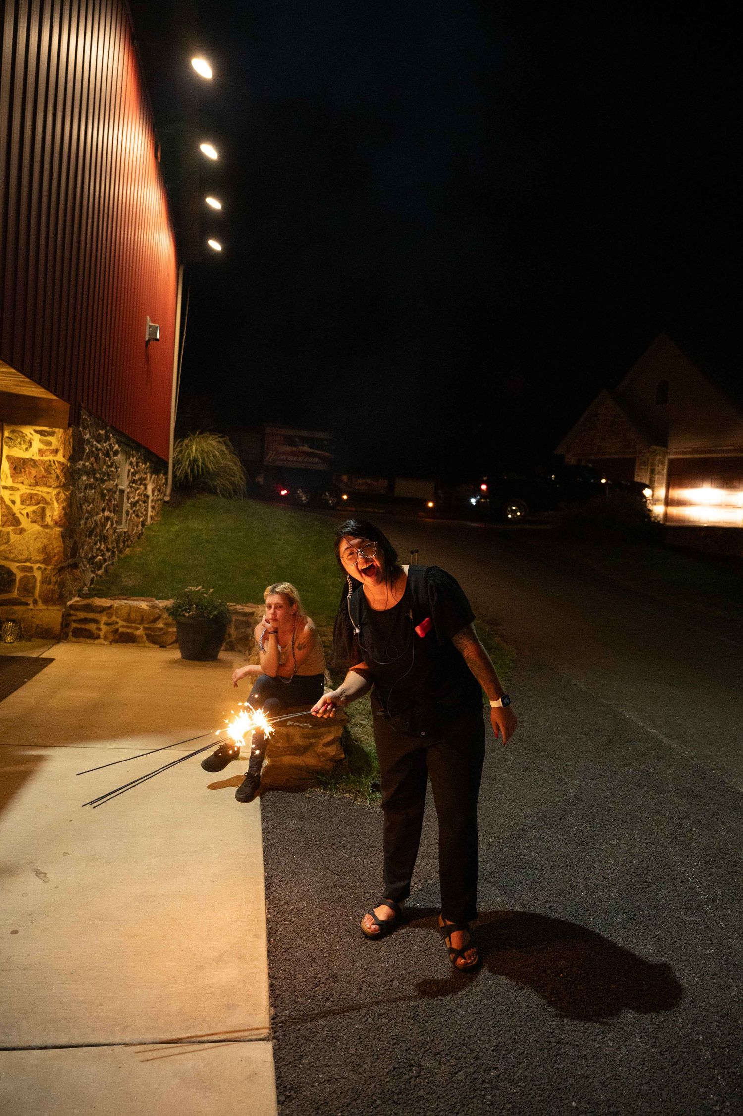 People lighting sparklers outside a building at night.