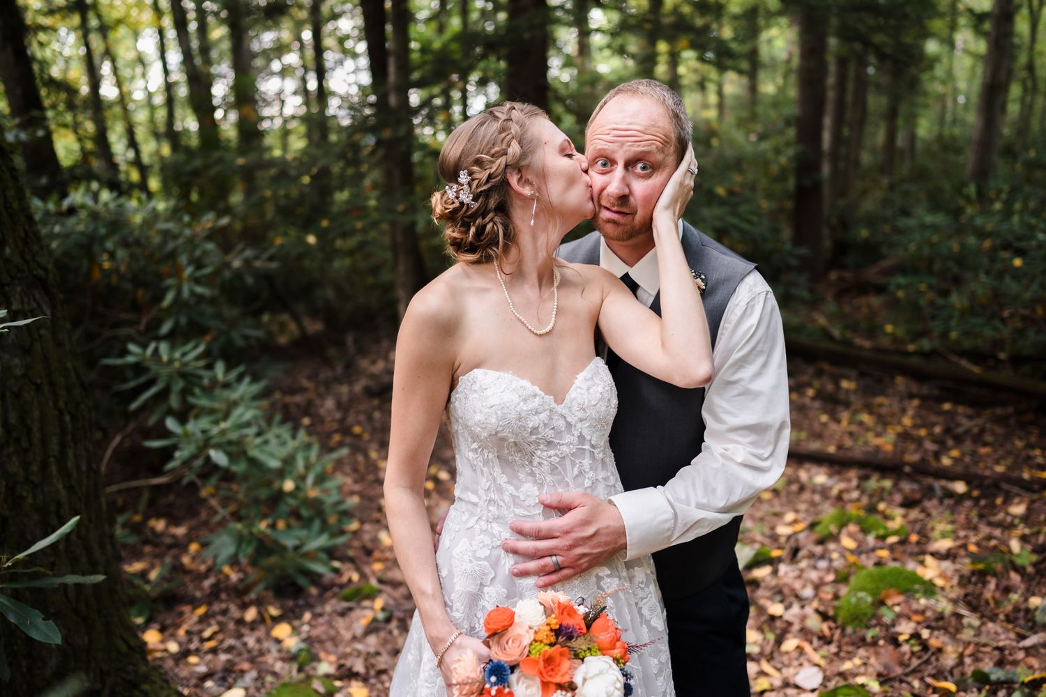 Wedding couple embraces in a romantic forest setting with natural lighting.