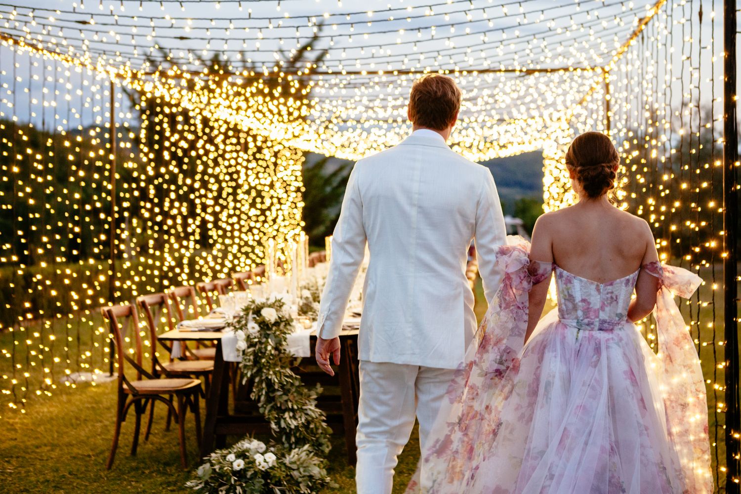 bride and groom walk under a canopy of fairy lights