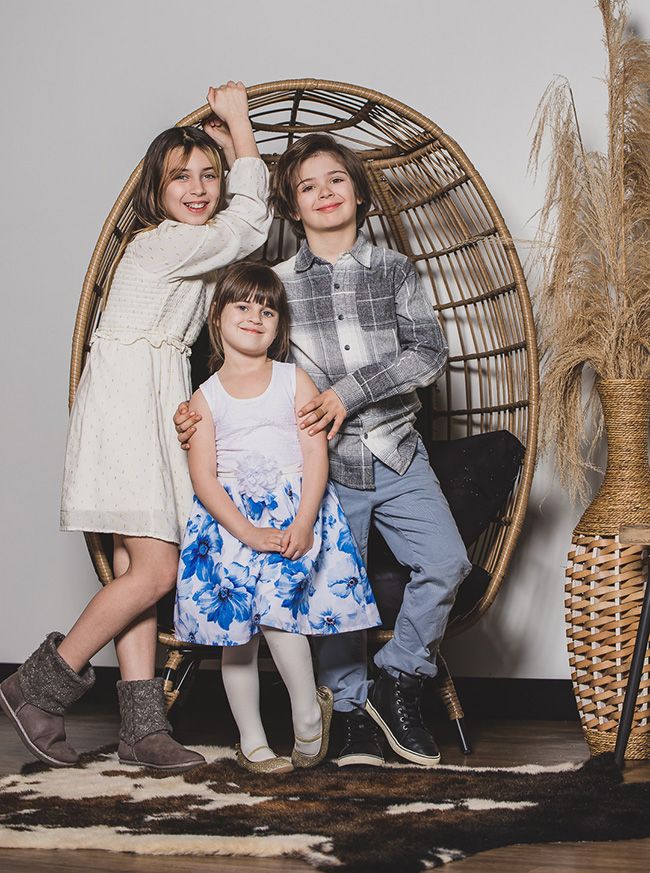 Sisters and brother standing in front of a hanging swing smiling together