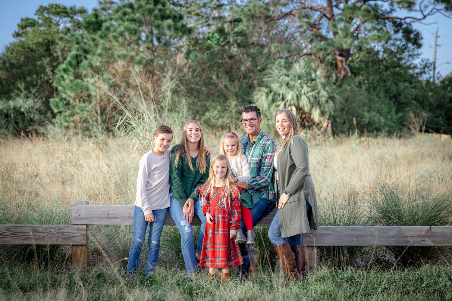 Family posing together in tall grass beside a wooden bench at Hobe Sound Scrub Preserve