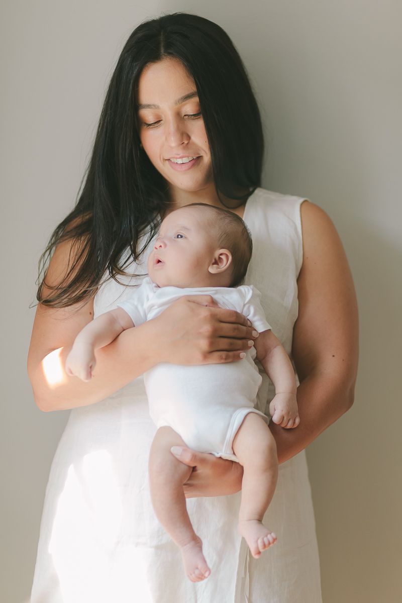 a mother looking at her newborn child with beautiful light by NYC Family Photographer Paula Ortiz