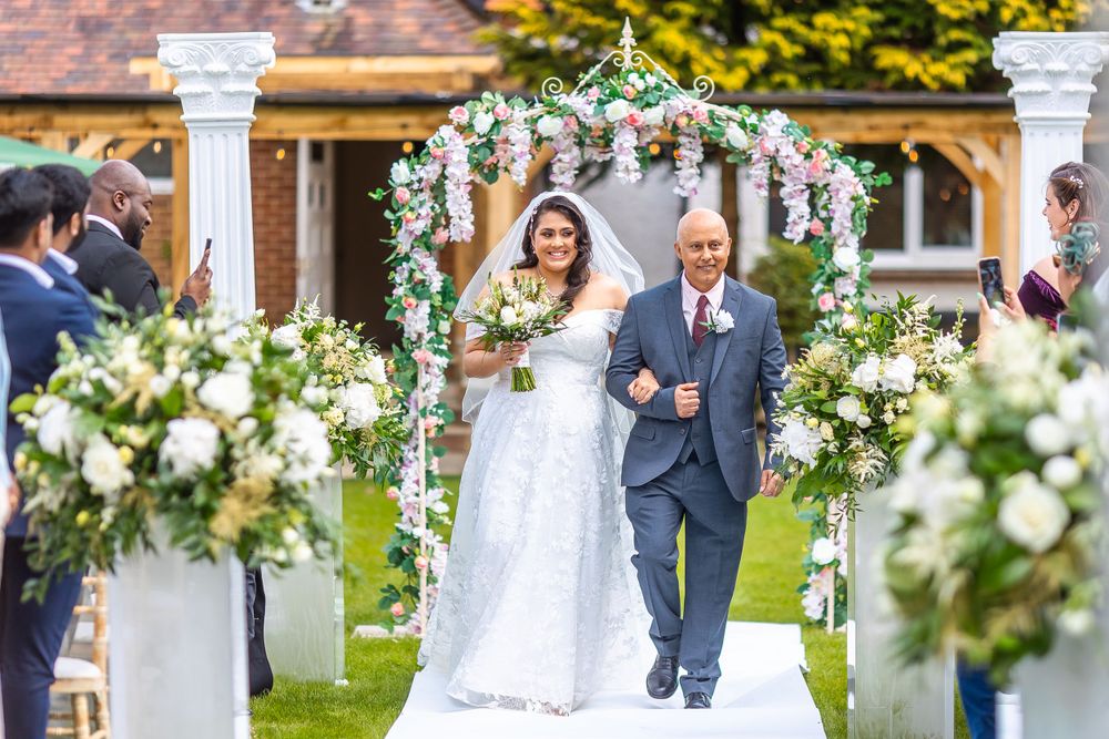 Beautiful outdoor wedding ceremony under a floral arch with white flowers.
