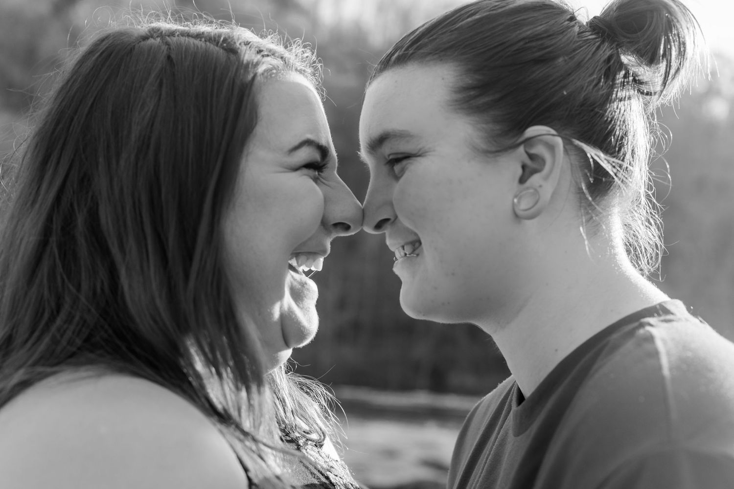 Romantic couple embraces near a waterfall in a black and white photo series.