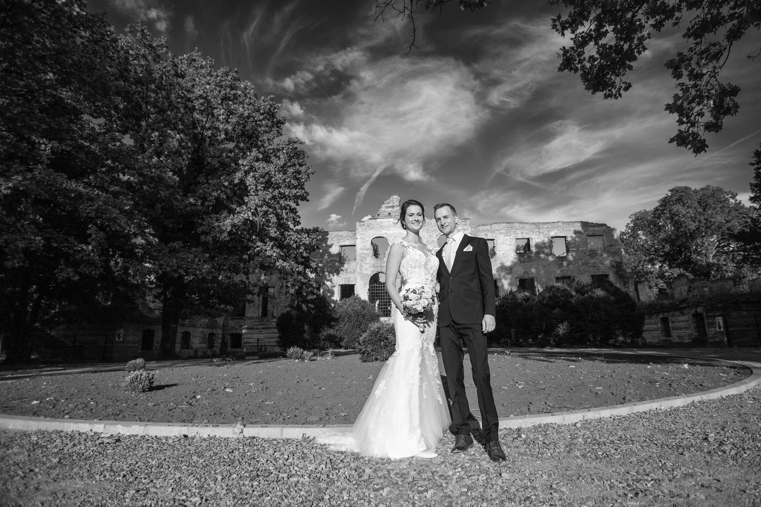 Black and white wedding portrait of couple standing before a grand historic building.