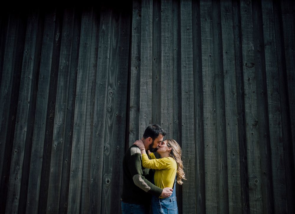 Silhouetted couple embracing against dark wooden wall background. Worcestershire Wedding photographer.