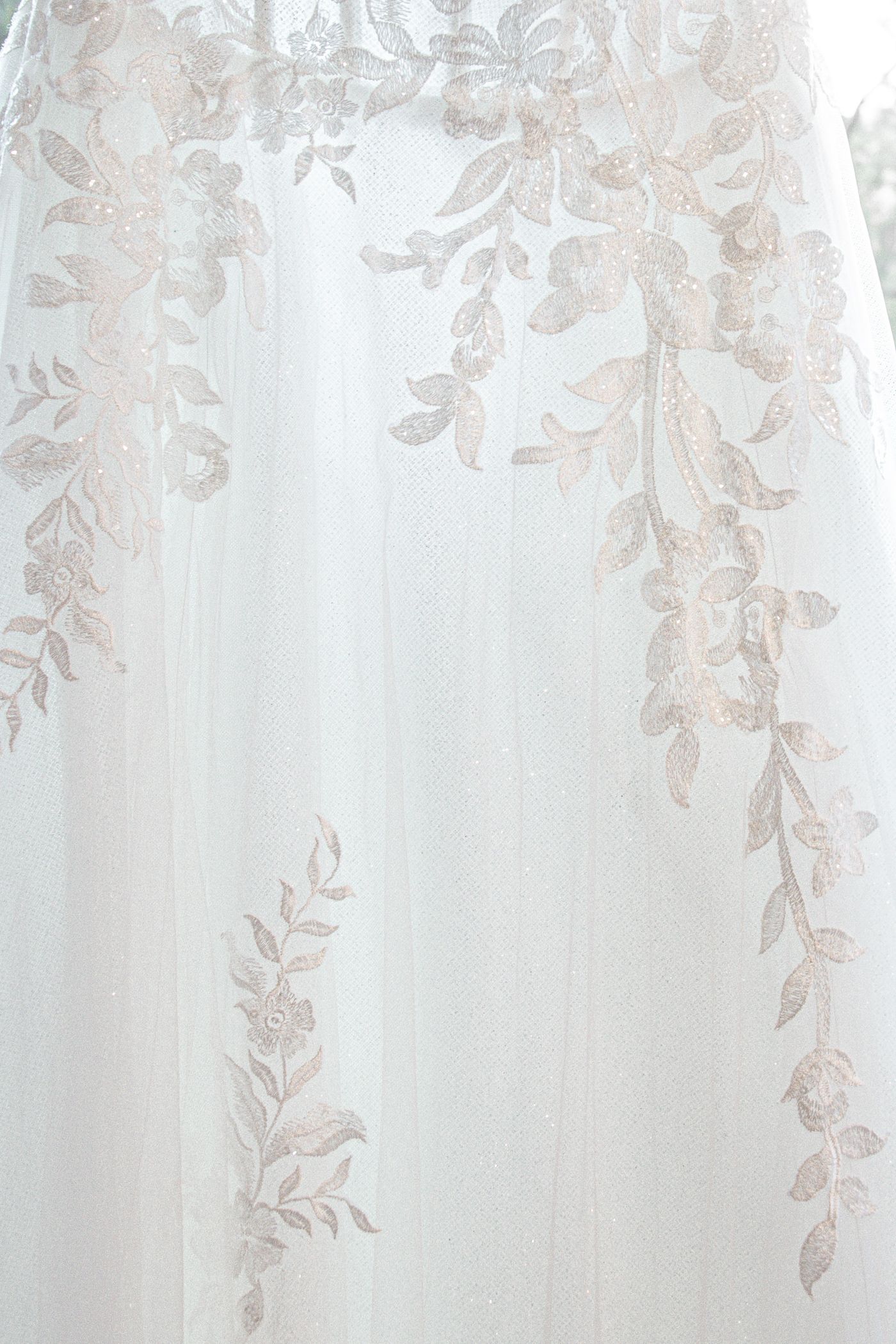Delicate floral lace embroidery detail on white wedding dress fabric.