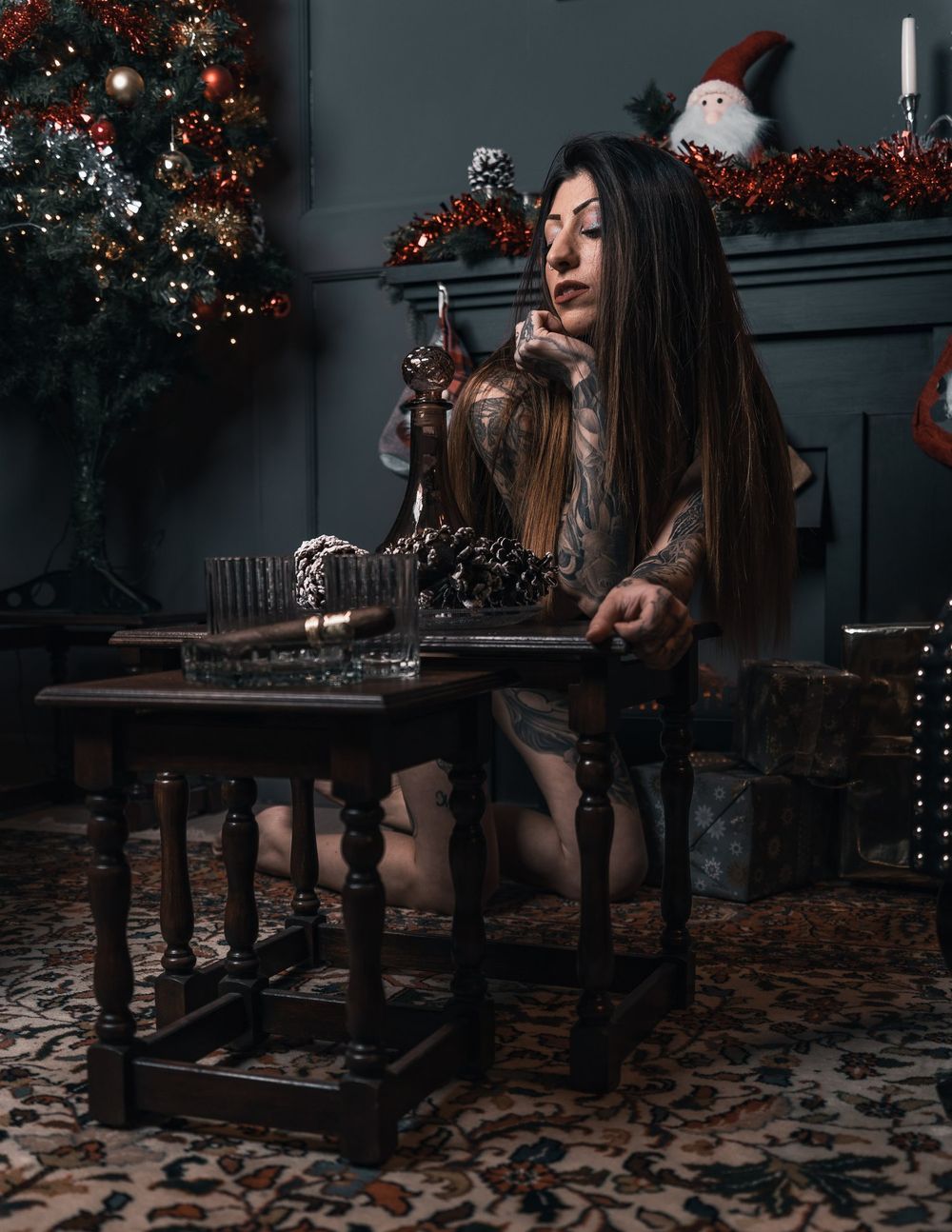 Moody Christmas scene with decorated tree and vintage furniture in dark setting.
