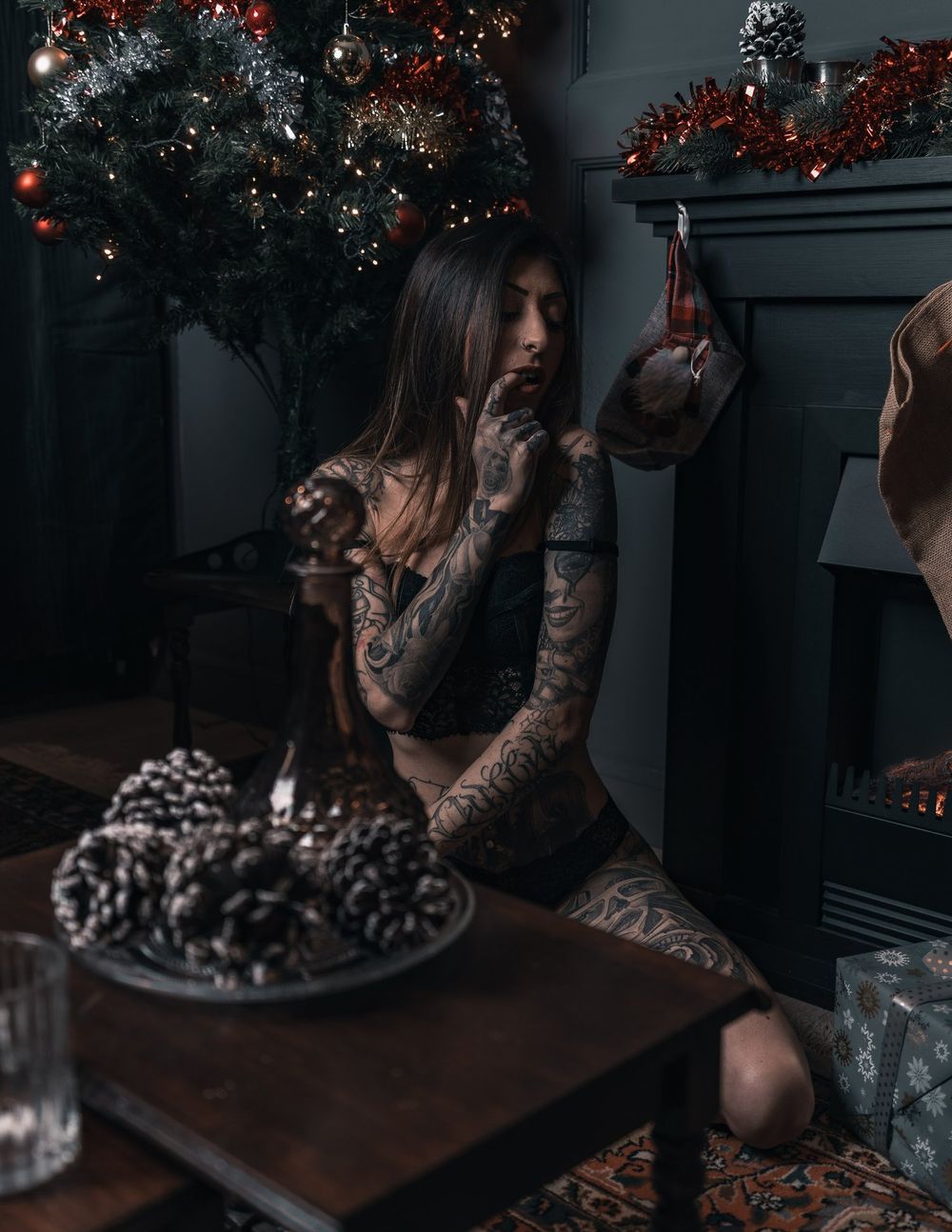 Dark and moody holiday scene with decorated Christmas tree and pinecone decorations.