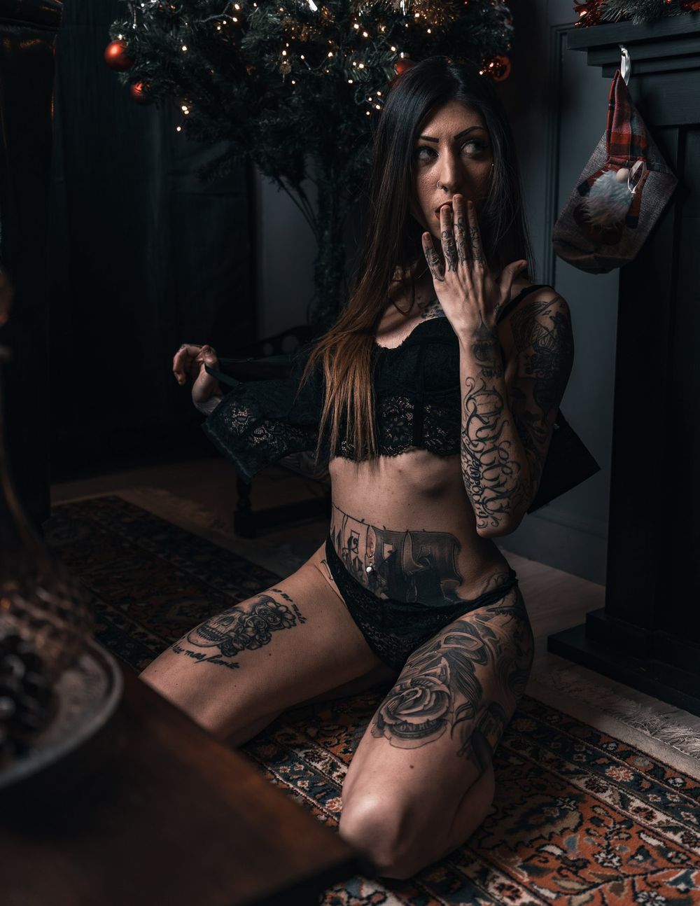 Sultry boudoir photography with extensive tattoos and holiday decorations in background.