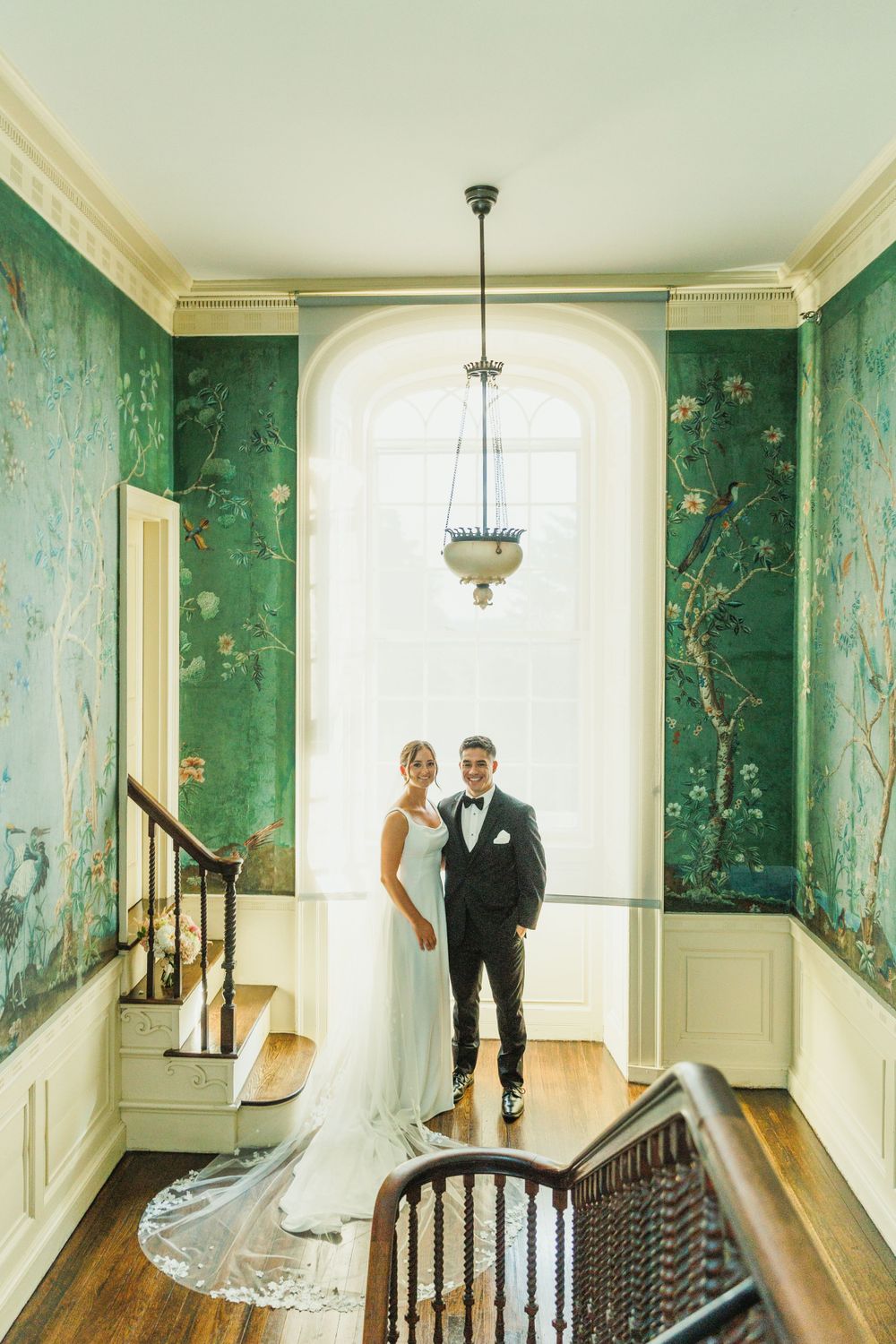 Bright hallway with ornate green wallpaper, hardwood floors and classic architectural details.