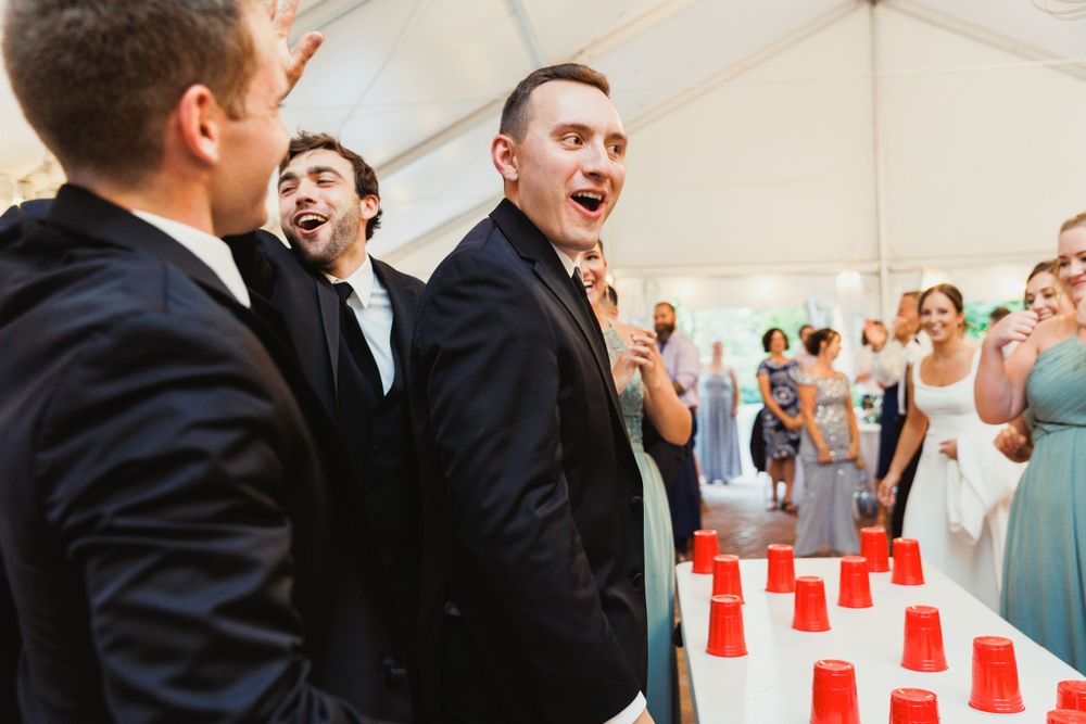 Guests react excitedly during a wedding reception game with red cups.