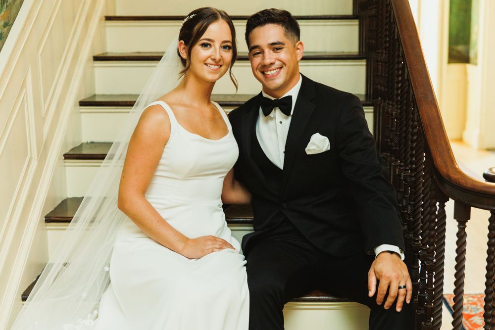 Wedding couple posing on antique staircase with elegant interior decor.
