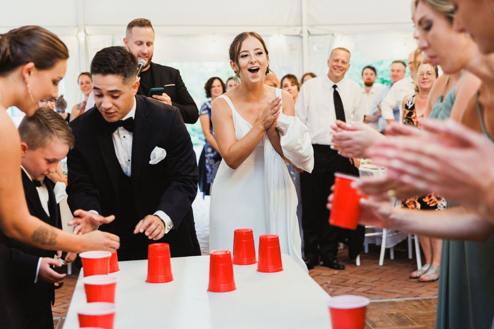 Wedding guests enjoying a lively party game with red cups at the reception.