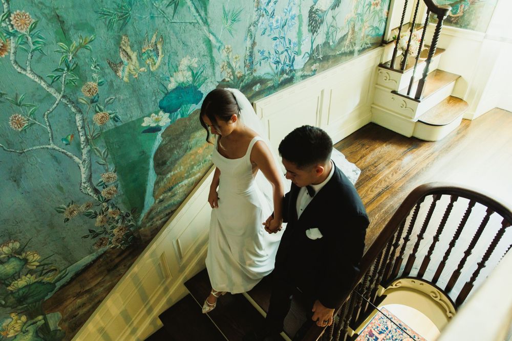 Couple sharing intimate moments in hallway with distinctive green chinoiserie wallpaper.