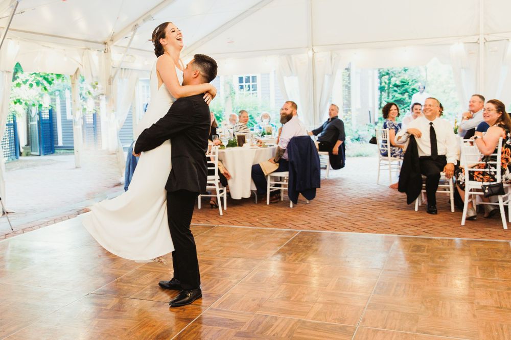 Romantic dance lift moment during a wedding reception in a tented venue.