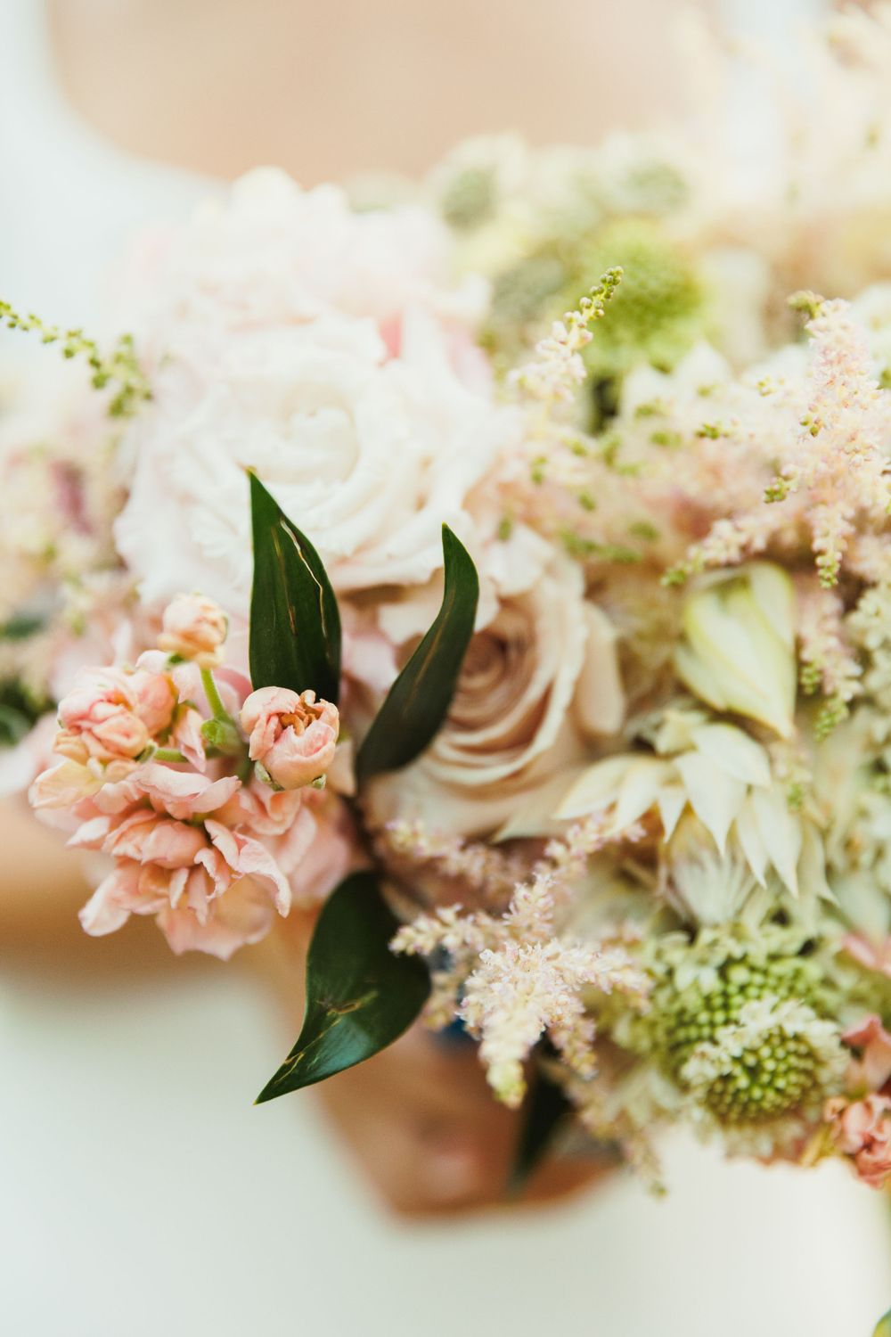 Soft pink and white floral arrangement with roses and delicate greenery in romantic pastel tones.