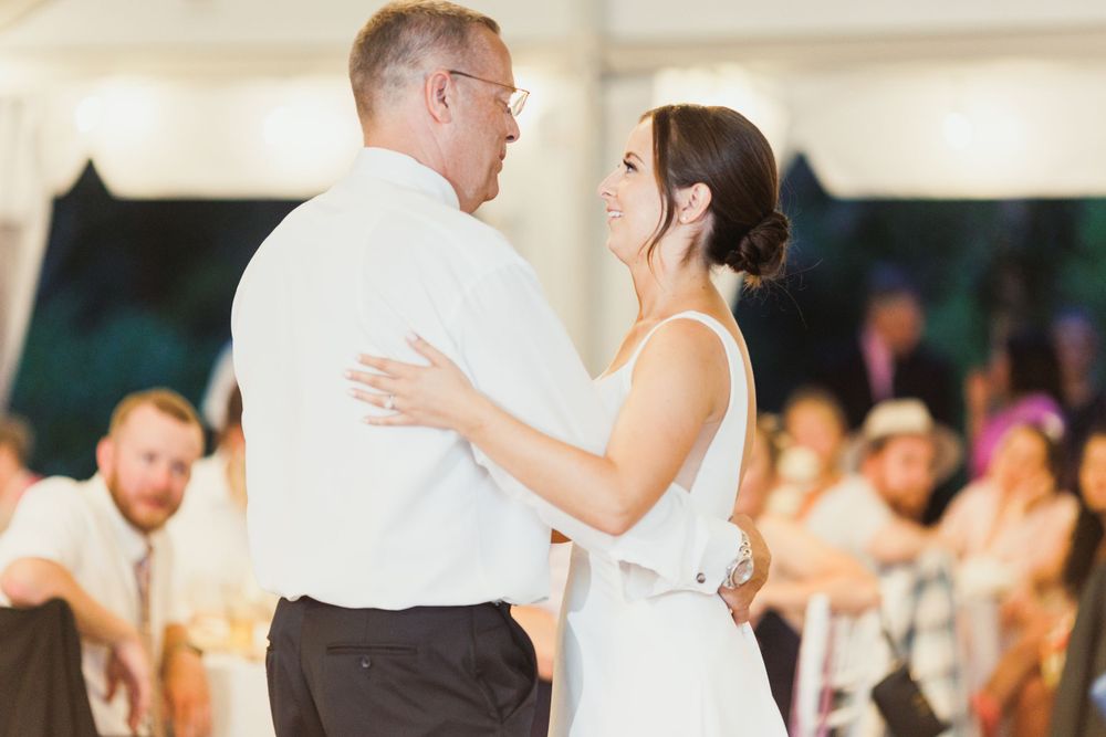 Couple shares intimate slow dance moment at tented wedding reception.