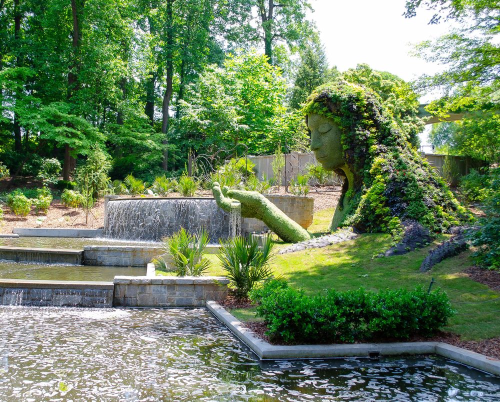 A scenic garden terrace with stone steps and a water feature surrounded by lush greenery and landscaping.
