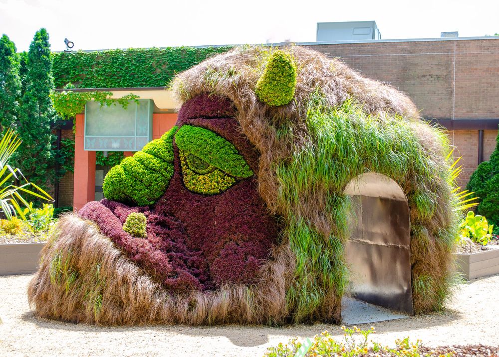 A whimsical plant sculpture of a giant creature with grass fur and moss features.