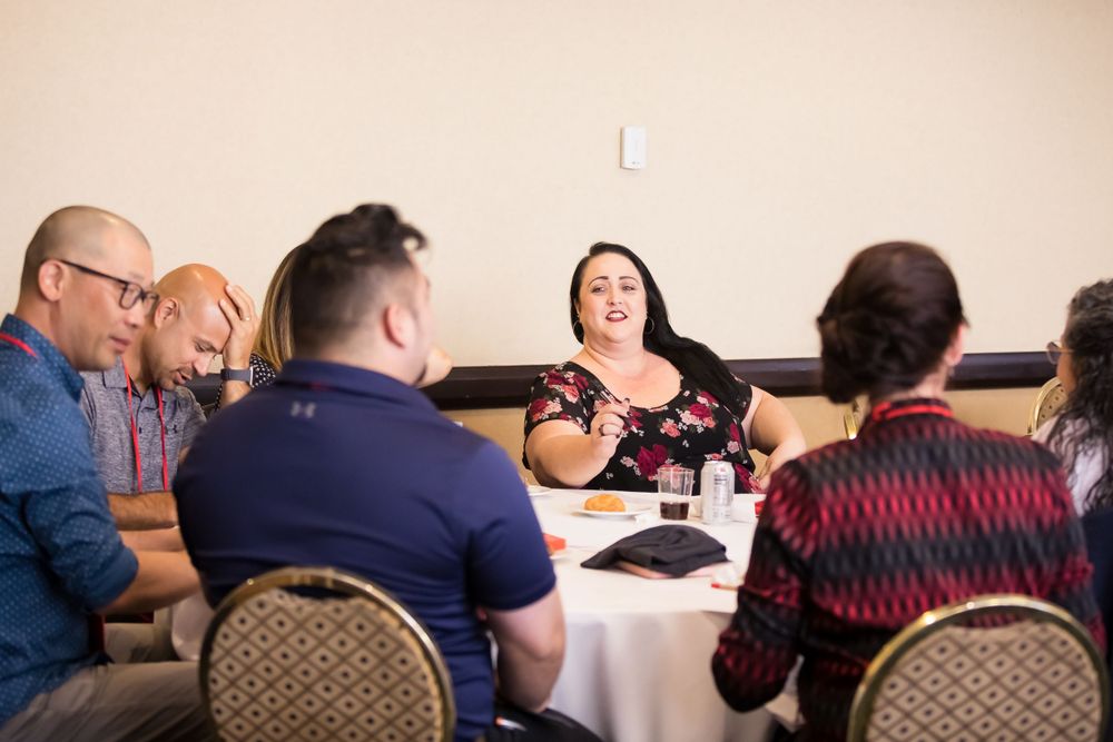 A group gathered around a round table during a conference workshop discussion.