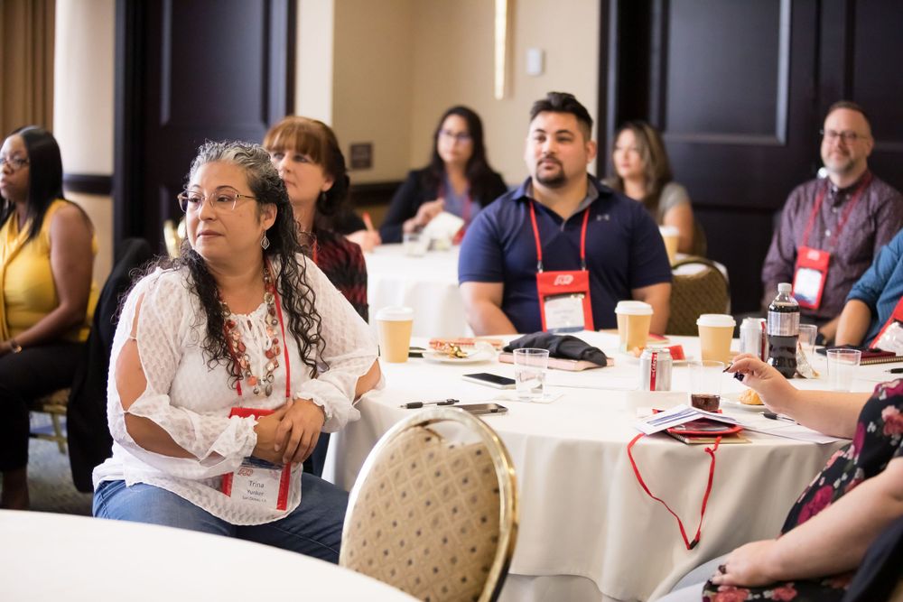 Conference attendees sit at round tables during a professional development workshop session.