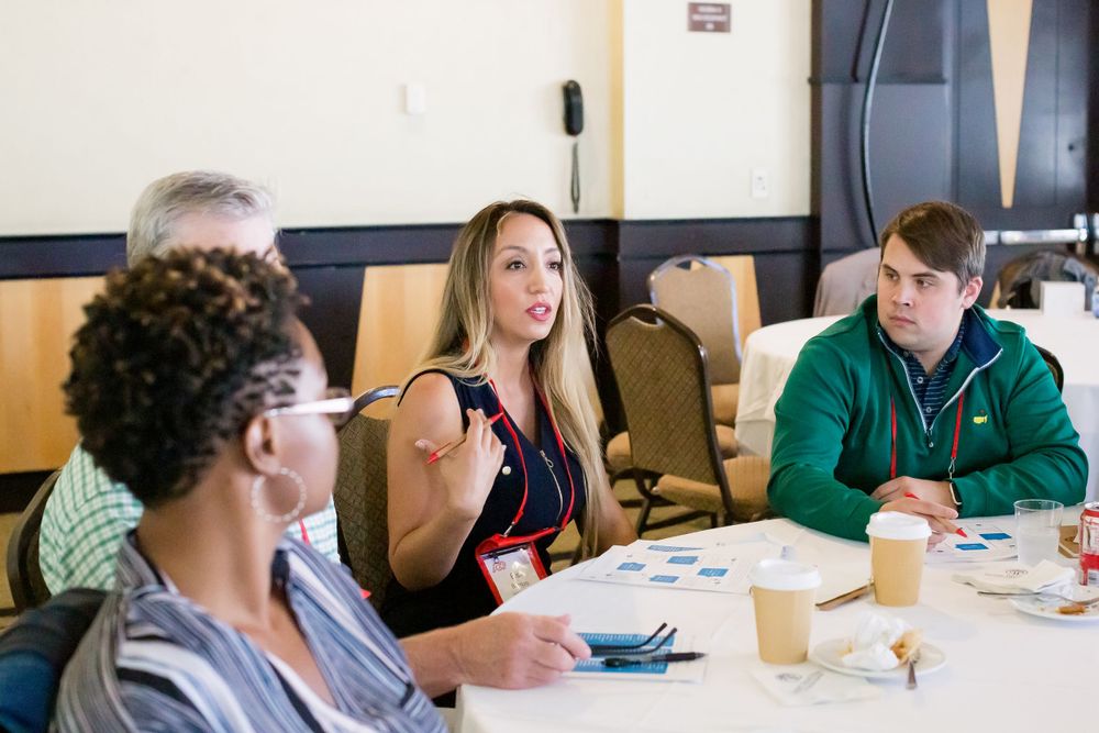 Small group discussion during professional workshop with participants seated at table.
