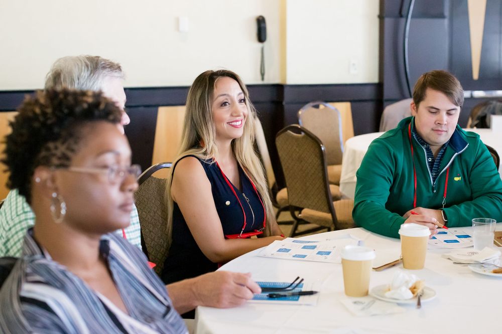 Diverse group of workshop participants engaged in discussion at conference table.