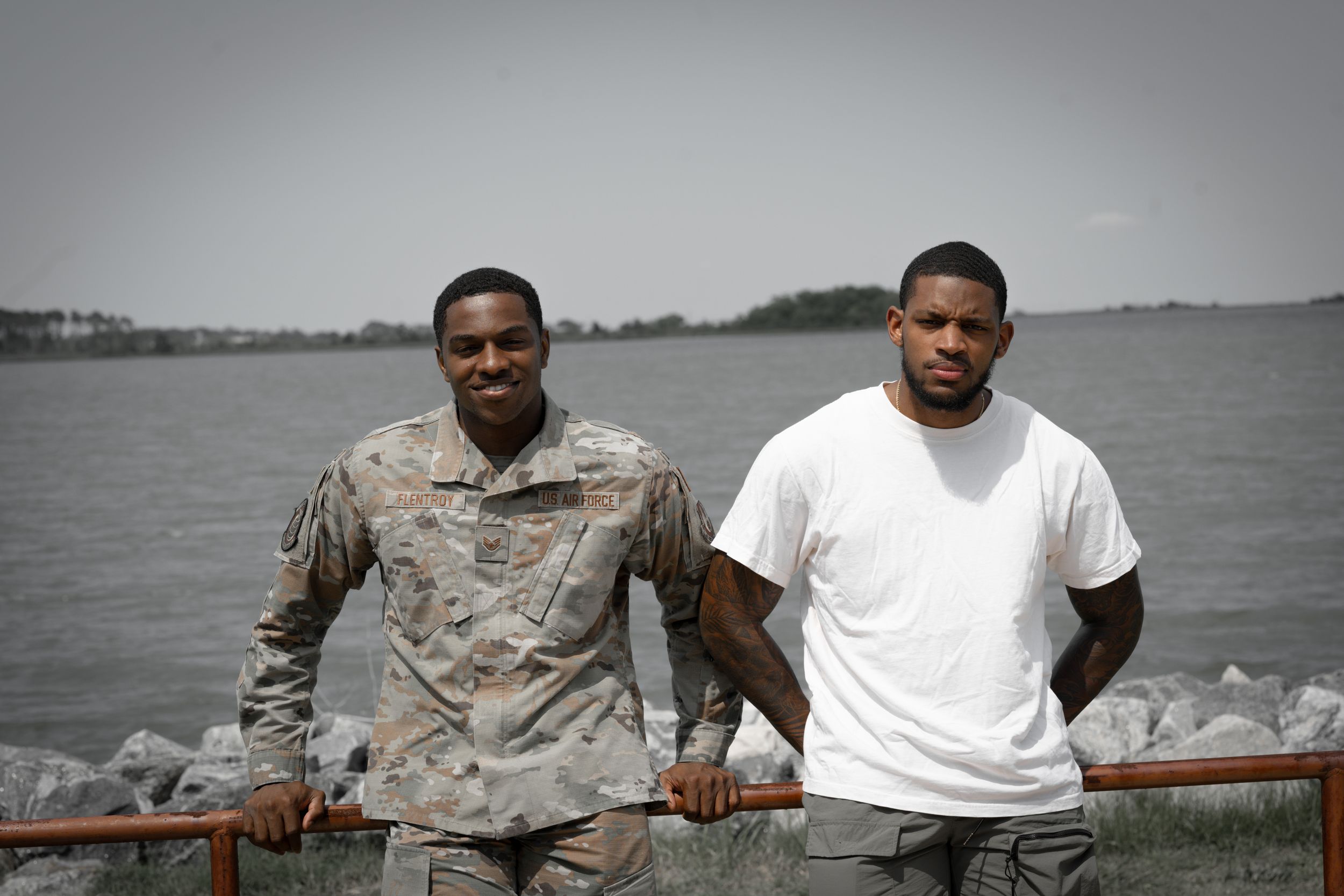 Two men standing together by a railing overlooking the water.