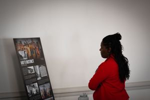 Person in red examining wall displays in gallery exhibition space.