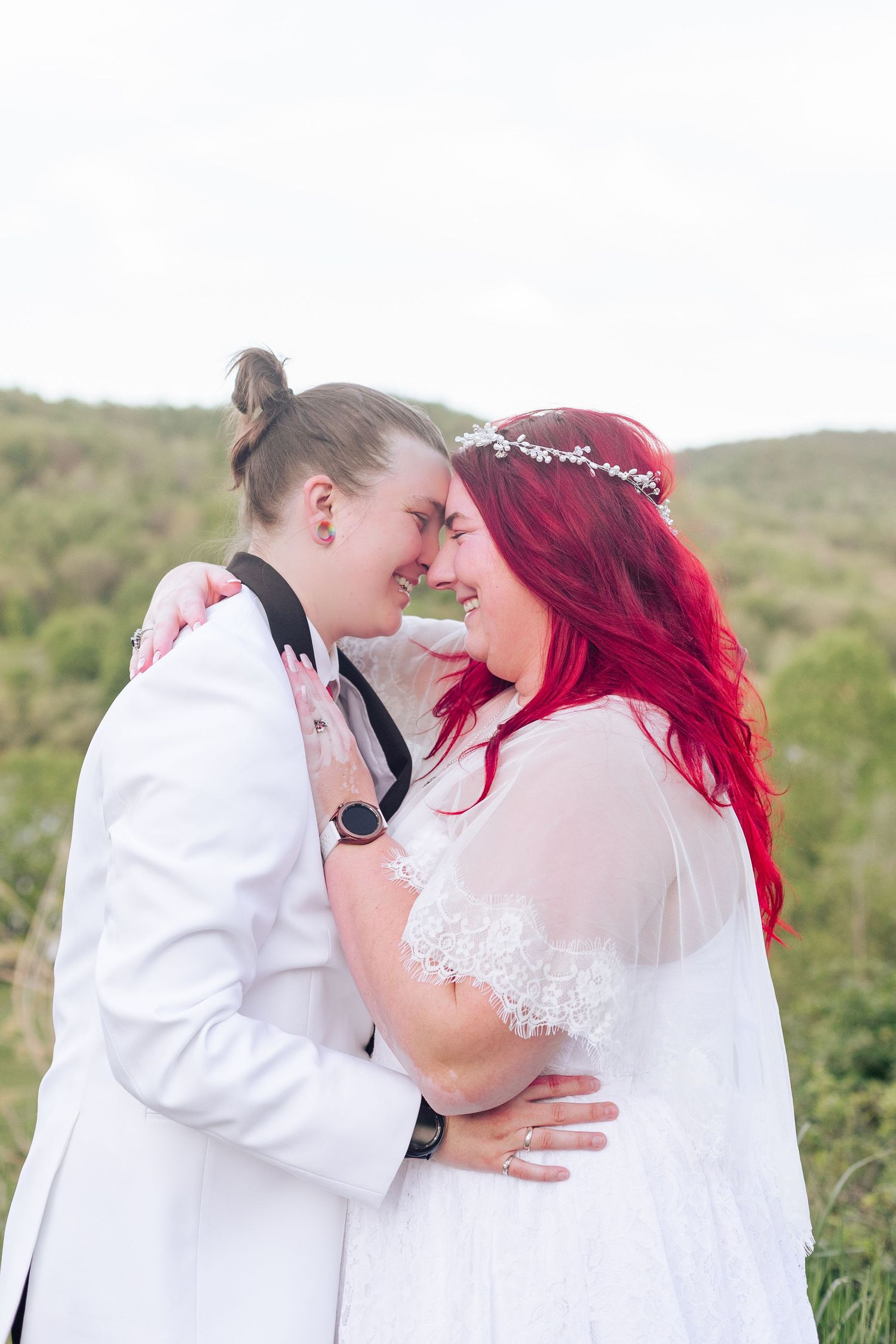 Romantic wedding moment captured in field with mountains and lake in background.