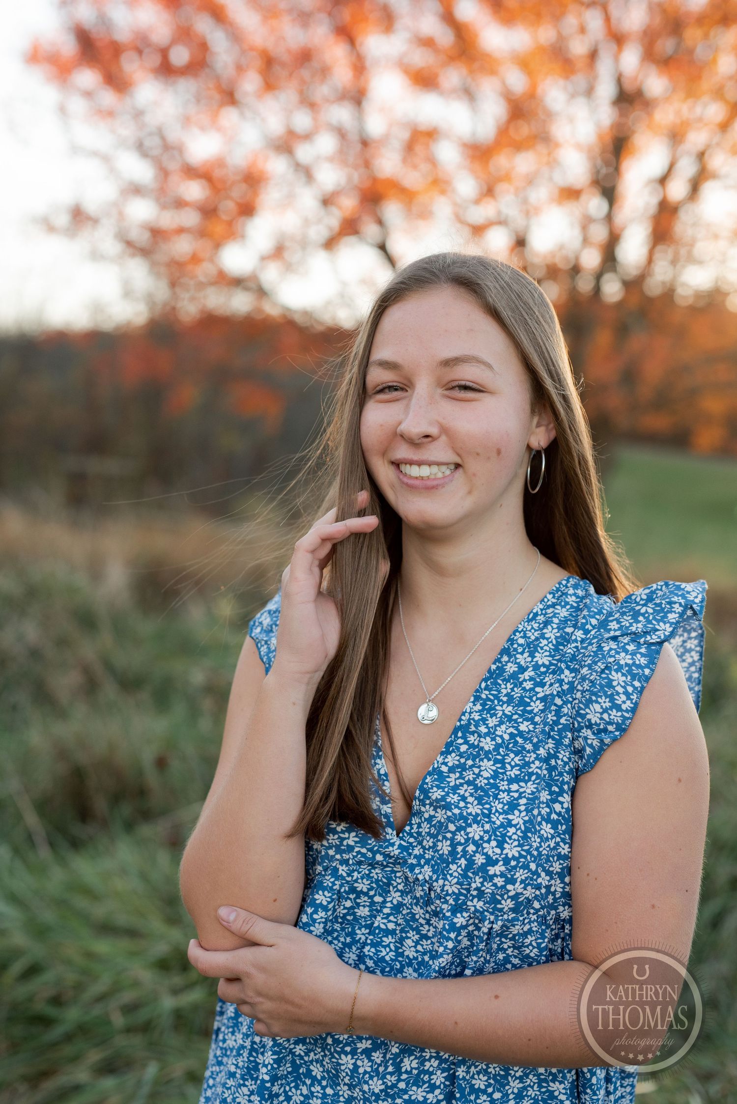 A blue floral dress with ruffled sleeves against vibrant fall foliage at sunset.