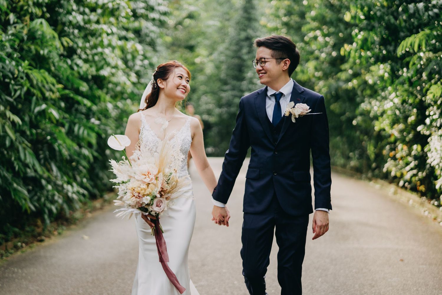 Newlyweds walking hand in hand down a lush garden path.