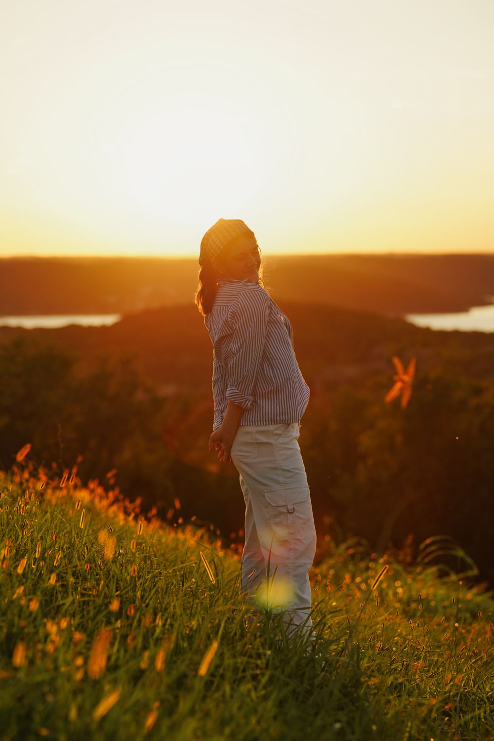 Senior portrait at sunset with lake in the background and warm golden light