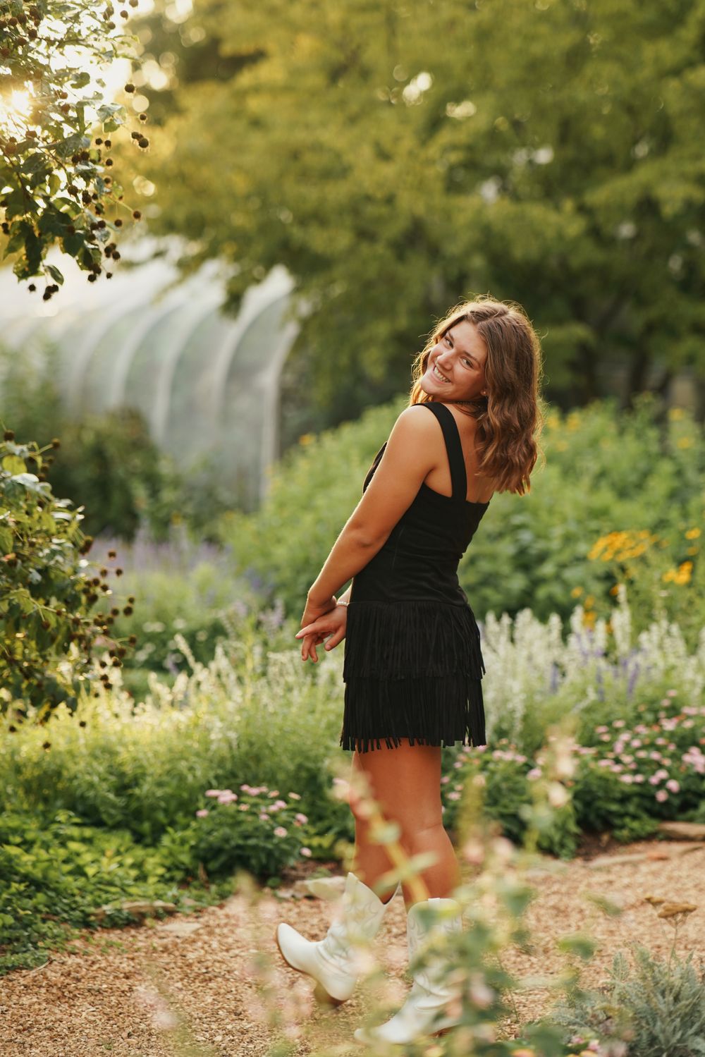 Senior portrait in lush garden with flowers and greenery in soft natural light