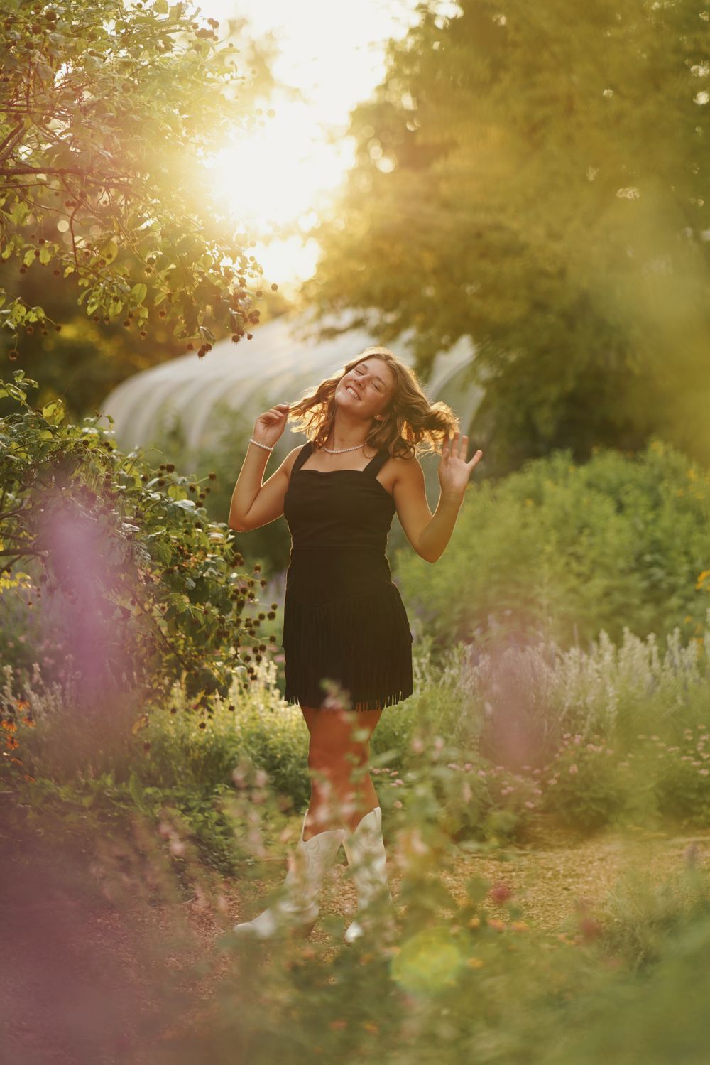 Senior portrait in lush garden with flowers and greenery in soft natural light