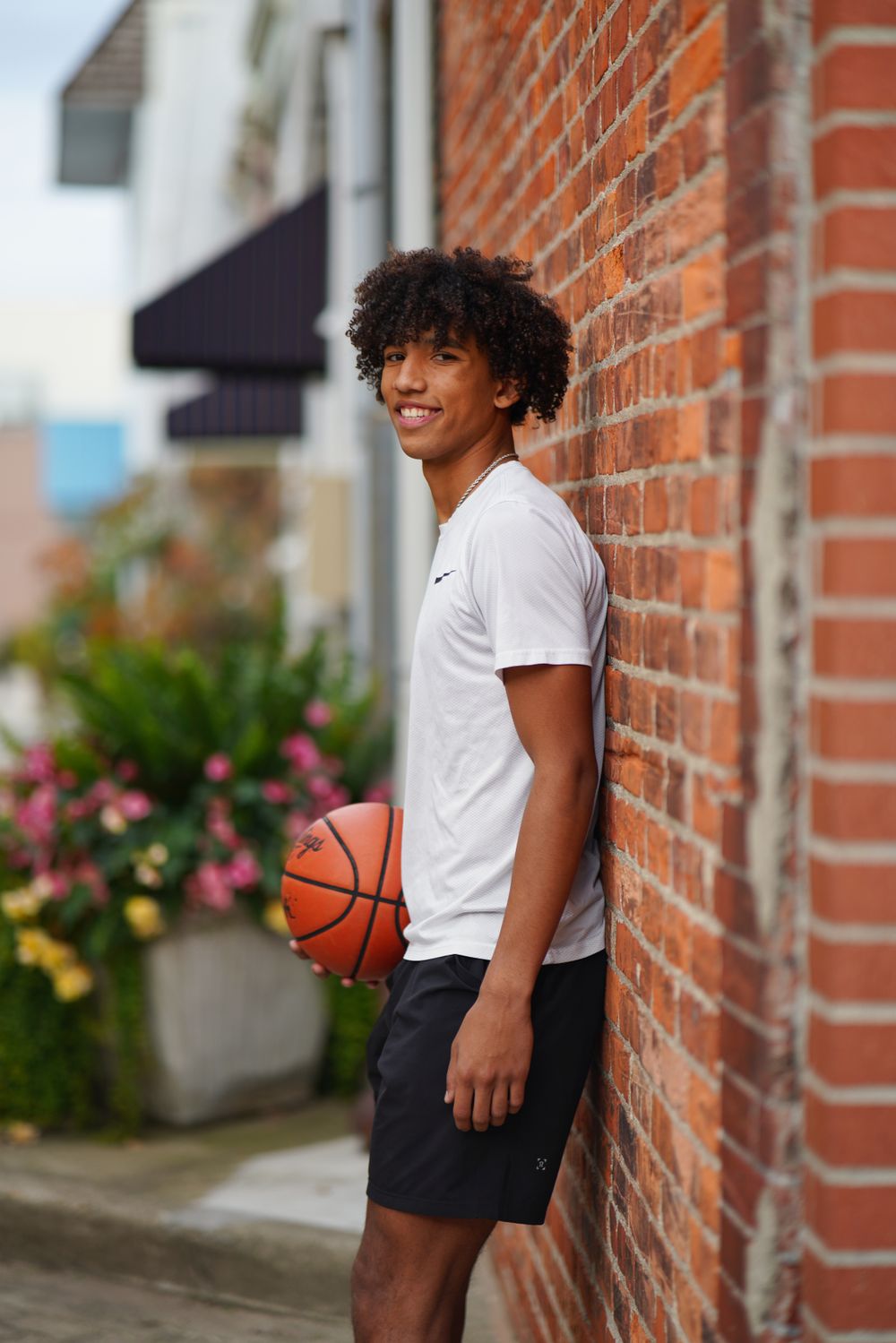 Senior portrait of young man holding basketball outdoors with natural light